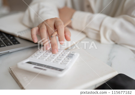 A close-up image of a woman using a calculator, examining her expenses, planning her savings A close-up image of a woman using a calculator, examining her expenses, planning her savings 115677182