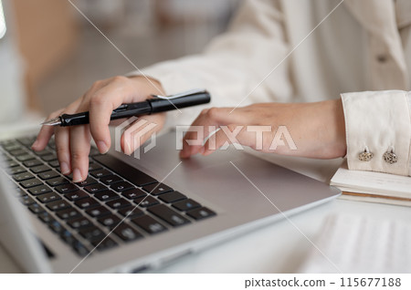 A close-up image of a businesswoman working on her laptop computer, typing on the laptop keyboard. 115677188