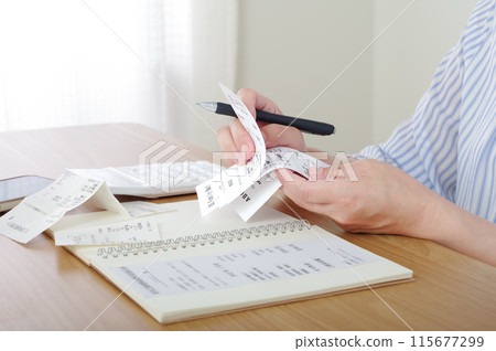 A woman who manages her finances by keeping a household account book 115677299