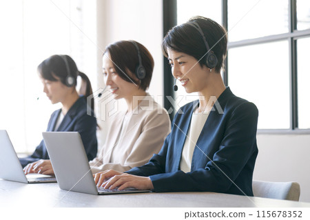 Women in a call center talking on an intercom 115678352