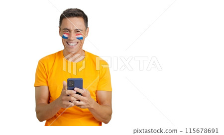 Dutch supporter looking at his mobile smiling and showing it. Dutch supporter looking at his mobile smiling and showing it. 115678691