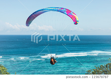 Paraglider flies in front of the ocean Paraglider flies in front of the ocean 115678787
