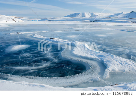 A frozen lake with a blue sky in the background A frozen lake with a blue sky in the background 115678992