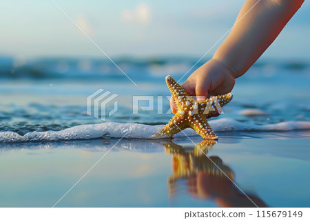 A child is holding a starfish on the beach 115679149