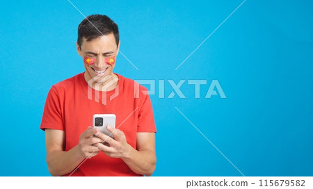 Vietnam supporter looking at his mobile smiling and showing it. Vietnam supporter looking at his mobile smiling and showing it. 115679582