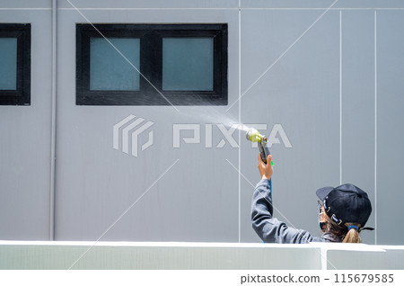 Female engineer using hose for testing window leak by spray water. Home inspection concepts. 115679585