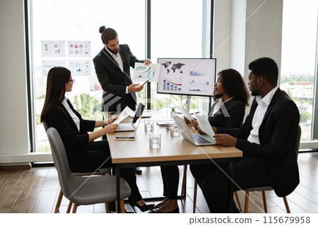 Business meeting with team discussing financial reports and graphs 115679958