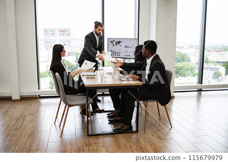 Businessman handing out papers during office meeting 115679979