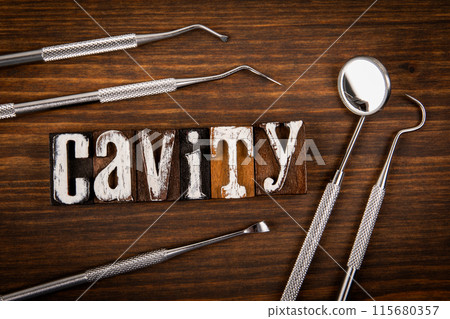 CAVITY. Dentist tools on wooden texture background CAVITY. Dentist tools on wooden texture background 115680357
