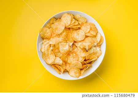 Crispy Potato Chips in bowl on Yellow Background. Top view. 115680479