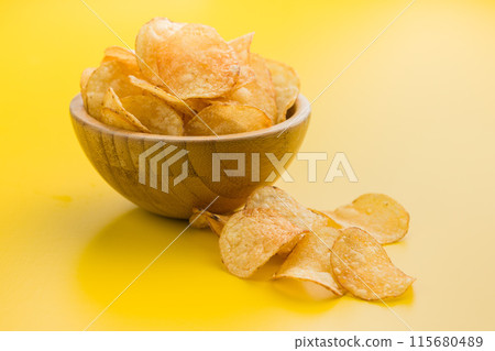Crispy Potato Chips in bowl on Yellow Background 115680489