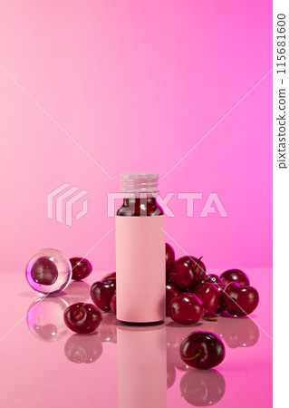 An unbranded high quality bottle of healthcare of beauty care products, which extracted from cherry. It is displayed on the pink table against the same color background with plenty cherries in back 115681600