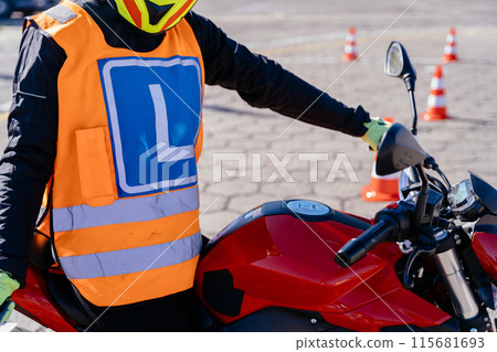 Concept of motorcycle school of driving. Close up of unrecognizable woman sitting on motorbike learns to drive before obtaining a driving license. 115681693