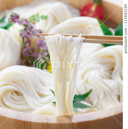 Lifting somen noodles from a tub with chopsticks (somen) 115683289