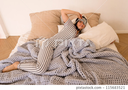 Woman stretching in bed with a joyful expression. Woman stretching in bed with a joyful expression. 115683521
