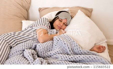 Woman sleeping peacefully in bed wearing eye mask. Woman sleeping peacefully in bed wearing eye mask. 115683522