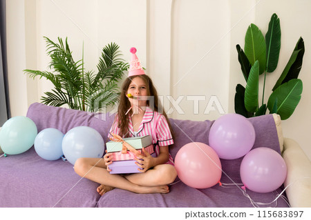Young girl celebrating her birthday at home, holding presents. Young girl celebrating her birthday at home, holding presents. 115683897