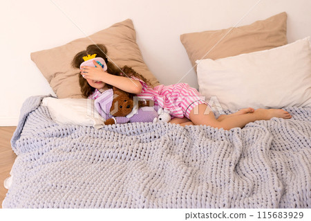 Child hiding face with sleep mask, holding teddy bear Child hiding face with sleep mask, holding teddy bear 115683929