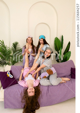 Sisters and mother tickling younger girl, creating laughter and joy Sisters and mother tickling younger girl, creating laughter and joy 115684257