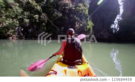 Man engages in kayaking making water splashes with paddle 115684459