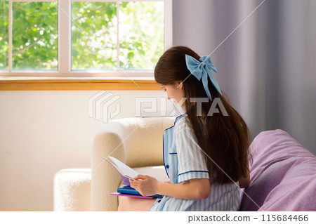Teenage girl reading book in cozy living room. Teenage girl reading book in cozy living room. 115684466