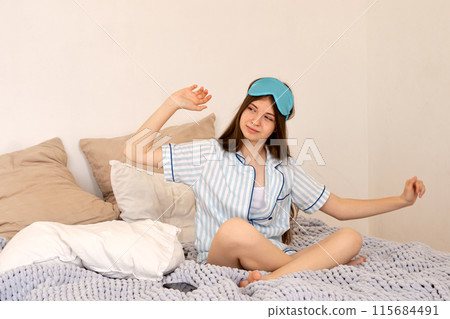 Teenager stretching with sleep mask pushed up on her forehead. Teenager stretching with sleep mask pushed up on her forehead. 115684491
