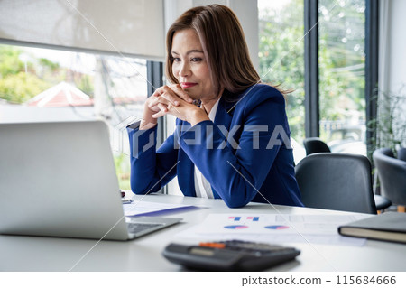 a young girl sits at a table in the office and holds a pen and works with documents 115684666