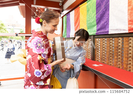 A foreign woman in a kimono drawing a fortune and a Japanese woman guiding her A foreign woman in a kimono drawing a fortune and a Japanese woman guiding her 115684752