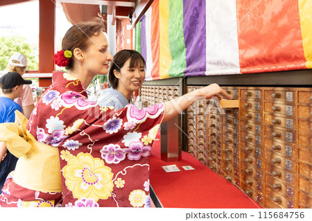 A foreign woman in a kimono drawing a fortune and a Japanese woman guiding her A foreign woman in a kimono drawing a fortune and a Japanese woman guiding her 115684756