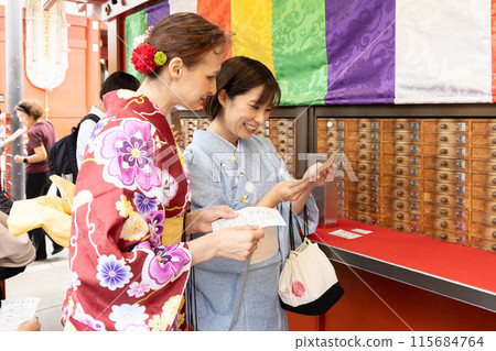 A foreign woman in a kimono drawing a fortune and a Japanese woman guiding her A foreign woman in a kimono drawing a fortune and a Japanese woman guiding her 115684764