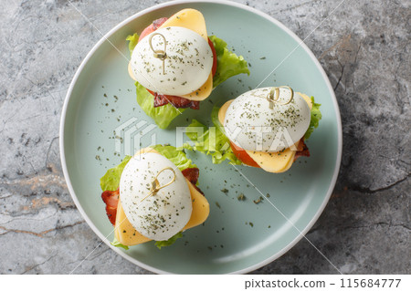 Snack bite sandwiches from deviled eggs with cheese, bacon, tomato and lettuce close-up in a plate. Horizontal top view 115684777