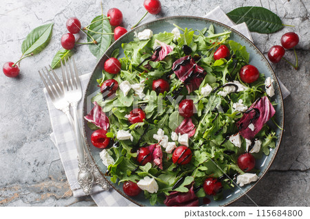 Spicy Cherry salad with arugula, radicchio and feta cheese dressed with balsamic dressing close-up in a plate. Horizontal top view 115684800