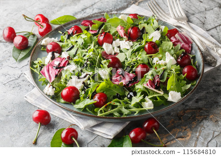 Spicy Cherry salad with arugula, radicchio and feta cheese dressed with balsamic dressing close-up in a plate. Horizontal 115684810