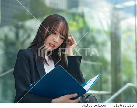 一名女商人在街角查看文件時憂心忡忡 115685130