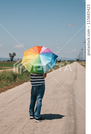 person carrying a rainbow umbrella 115685423