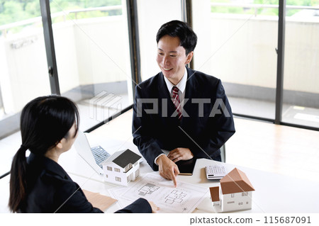 男性和女性商人在建築模型前交談 115687091