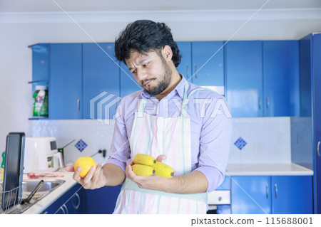 A man wearing an apron is worried about holding an orange and a banana A man wearing an apron is worried about holding an orange and a banana 115688001