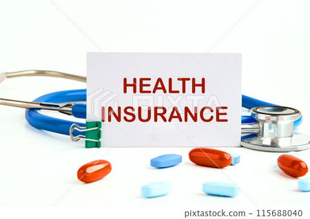Health insurance text written on a business card next to a stethoscope with pills, vitamins Health insurance text written on a business card next to a stethoscope with pills, vitamins 115688040