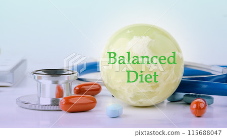 Balanced Diet text written on a ball on a light background on a ball on a blue background with pills and a stethoscope in the composition 115688047