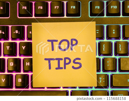 Business concept. Text TOP TIPS on a yellow sticker lying on the keyboard with a colored backlight Business concept. Text TOP TIPS on a yellow sticker lying on the keyboard with a colored backlight 115688158