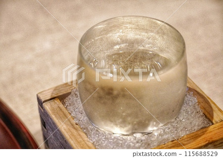 A glass of chilled sake in a masu (Japanese sake cup) with ice 115688529
