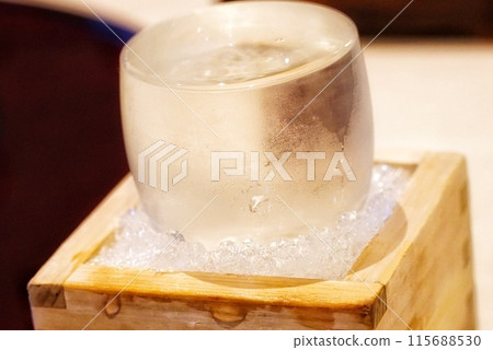 A glass of chilled sake in a masu (Japanese sake cup) with ice 115688530