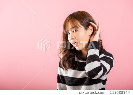 Asian portrait beautiful cute young woman teen smiling overhearing listening sound to gossip with attention with her hand on ear studio shot isolated on pink background with copy space hearing gesture Asian portrait beautiful cute young woman teen smiling overhearing listening sound to gossip with attention with her hand on ear studio shot isolated on pink background with copy space hearing gesture 115688544