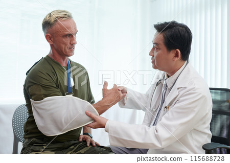 Doctor Putting Bandage On Arm Of Soldier Doctor Putting Bandage On Arm Of Soldier 115688728