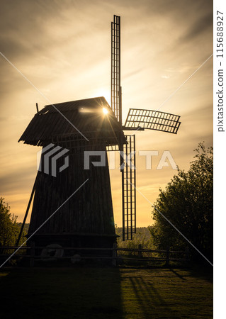Old wooden windmill on a sunset. Vertical silhouette photo 115688927