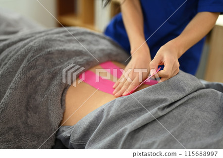 Close up physiotherapist applying on the patient back for relief of lower back pain. Rehabilitation and alternative medicine concept 115688997