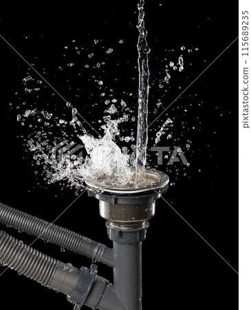 Drain sink leak water from pipe plumbing in bathroom as water splash clogged drop. Pouring Leaking water from gray plastic pipe drain sink. Black background isolated 115689235