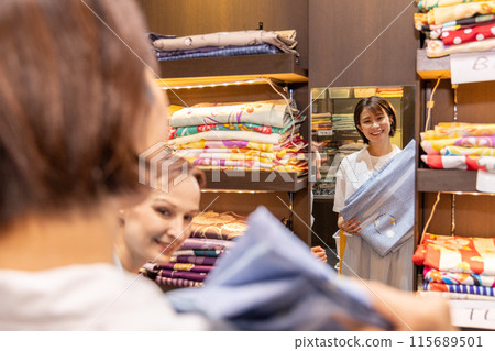 A foreign woman choosing a kimono at a rental store and a Japanese woman guiding her 115689501