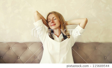 Happy relaxed young woman enjoying at home sitting on the couch in living room Happy relaxed young woman enjoying at home sitting on the couch in living room 115689544