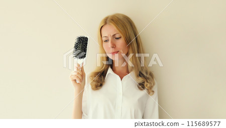 Unhappy disappointed young woman with hair loss condition, showing hair brush, unhealthy hair 115689577